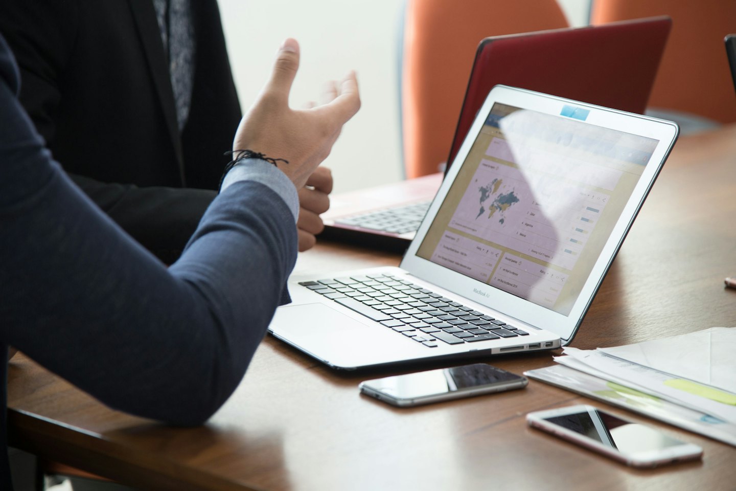 Profesionales de negocios discuten datos en una laptop en una mesa de conferencias.
