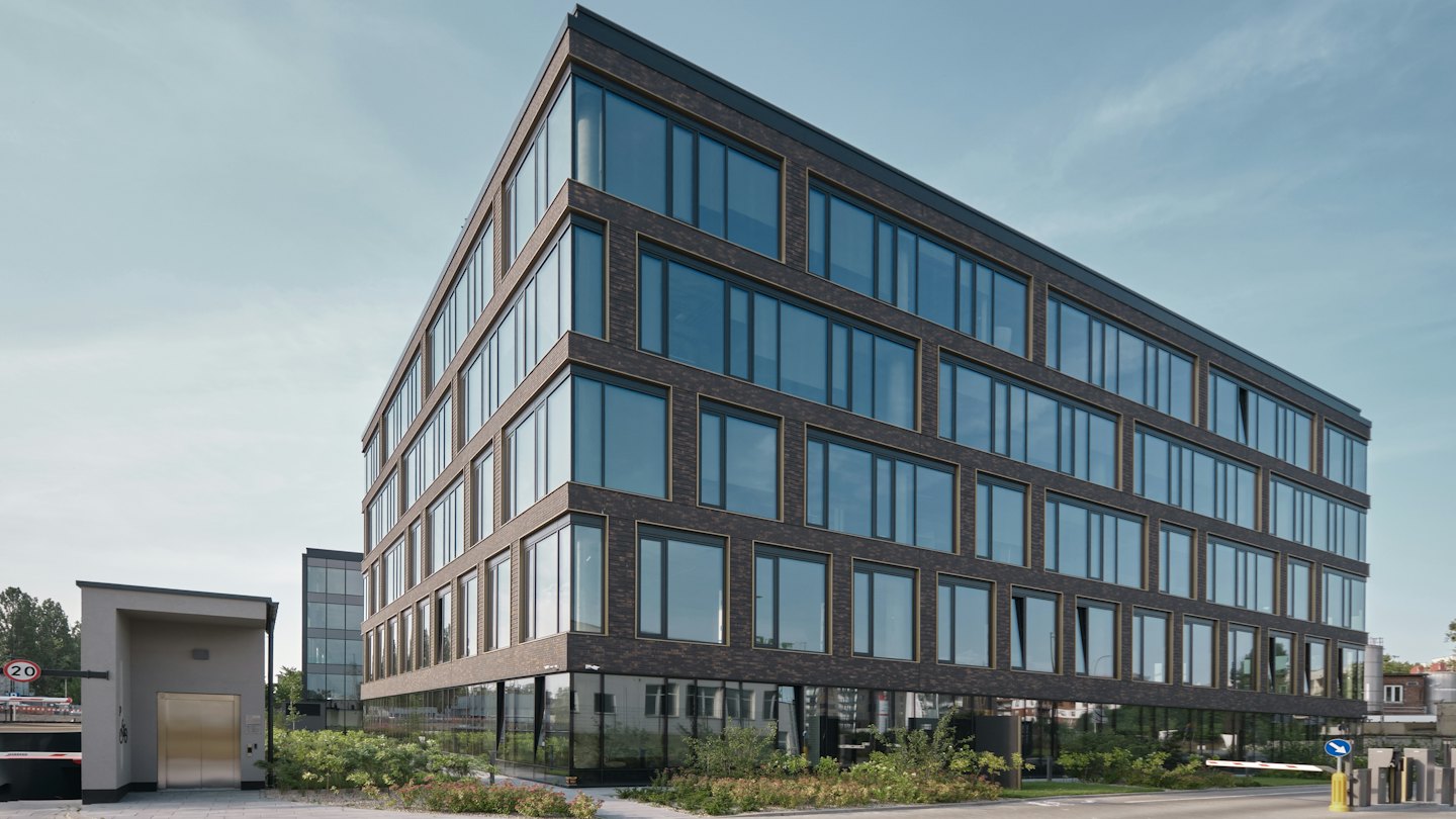 Edificio de oficinas moderno de ladrillo oscuro y ventanas reflectantes.