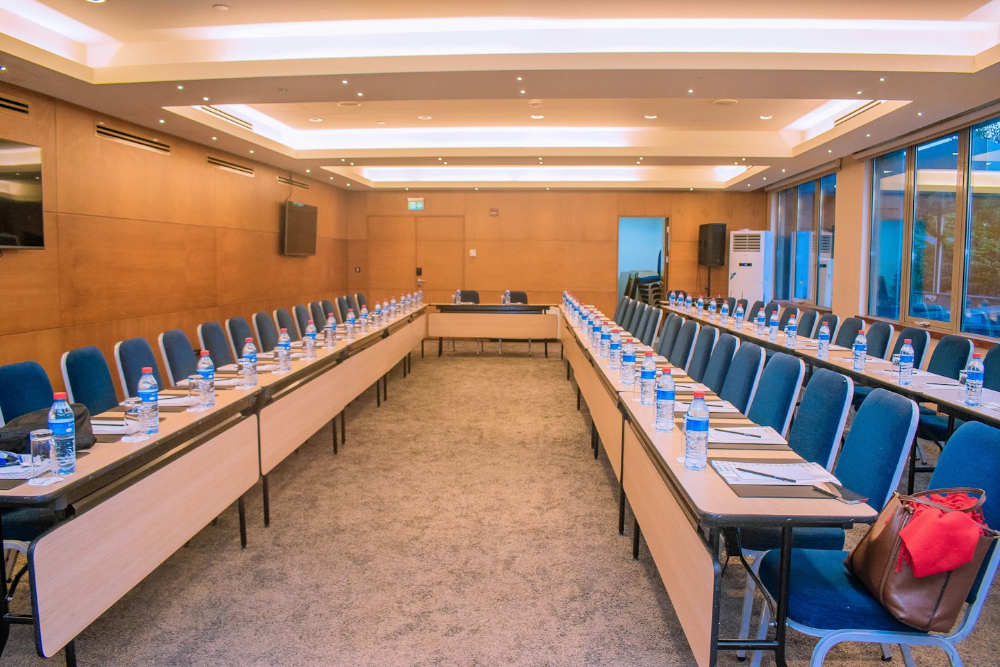 Sala de conferencias moderna con mesas de madera dispuestas para una reunión.